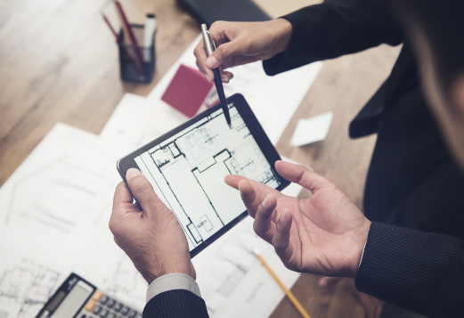 Die Mitarbeiter unterhalten sich an einem Tablet über den darauf angezeigten Bauplan des Immobilienobjekts
