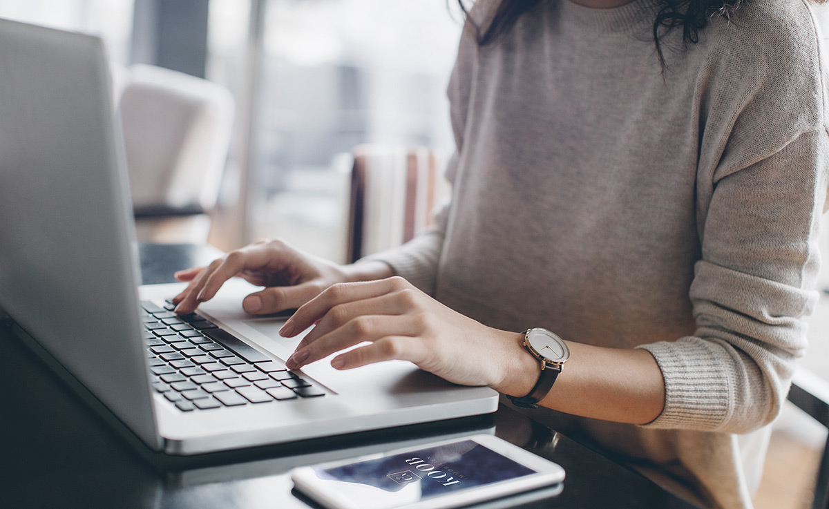 Zeigt eine junge Mitarbeiterin die an Ihrem Laptop arbeitet